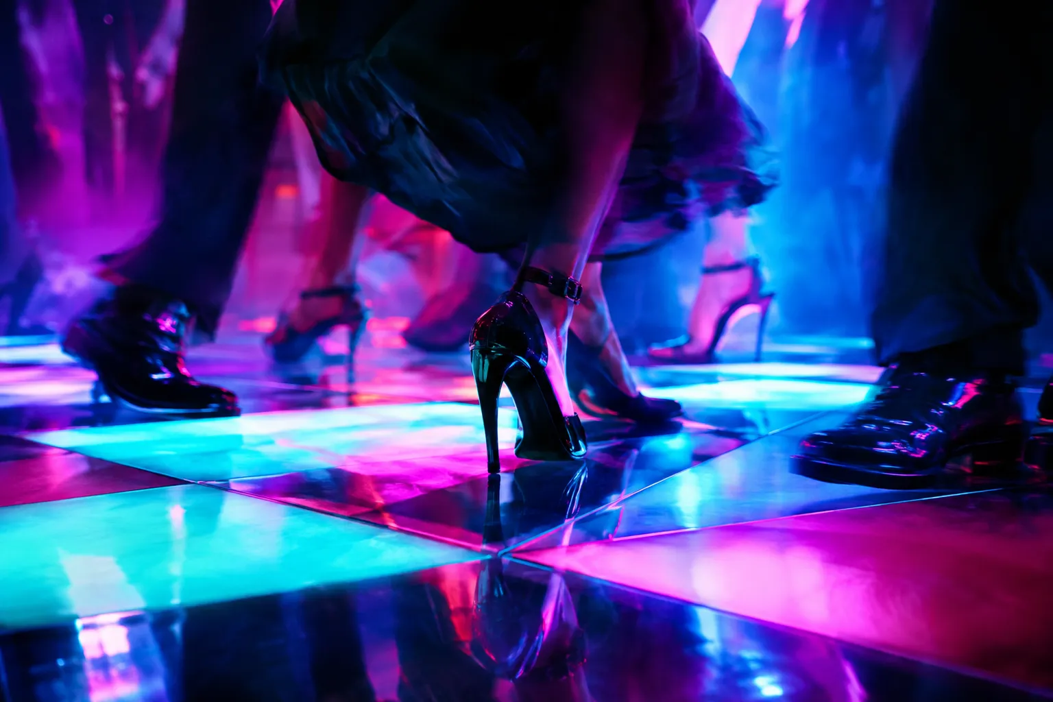 Detalhe de uma pista de dança LED com azulejos de luz ciano e magenta sob os pés dos convidados