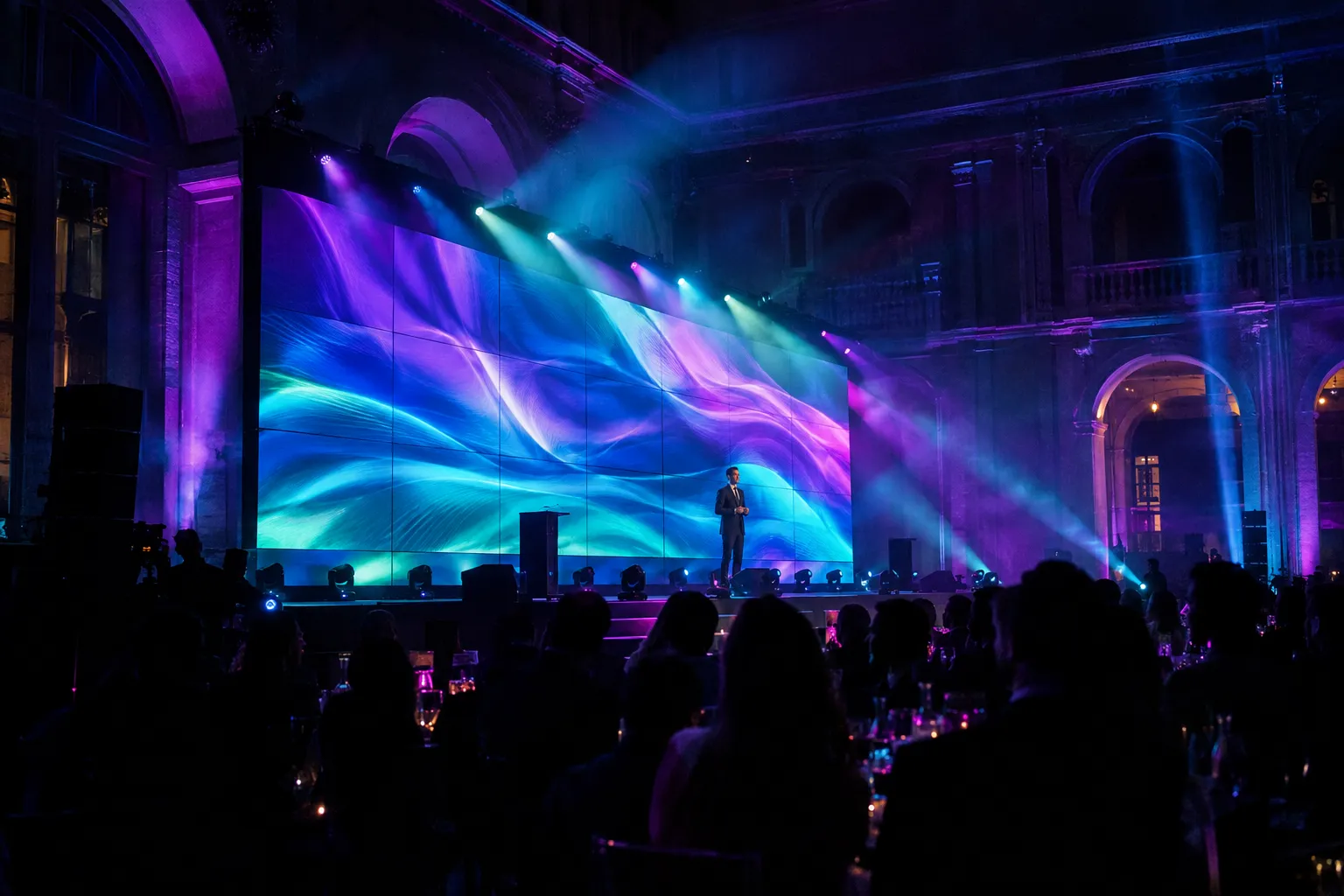 LED wall gigante num palco de gala corporativa com feixes de luz